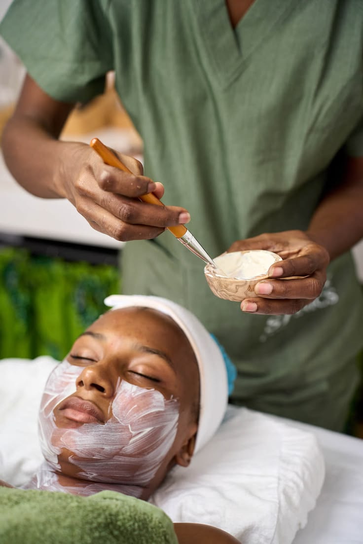 Skincare professional performing a facial on a Black woman